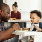 dad feeding baby in high chair